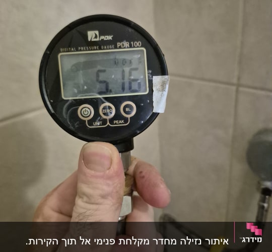מד לחץ דיגיטלי מוחזק ביד, צינור מים ברקע